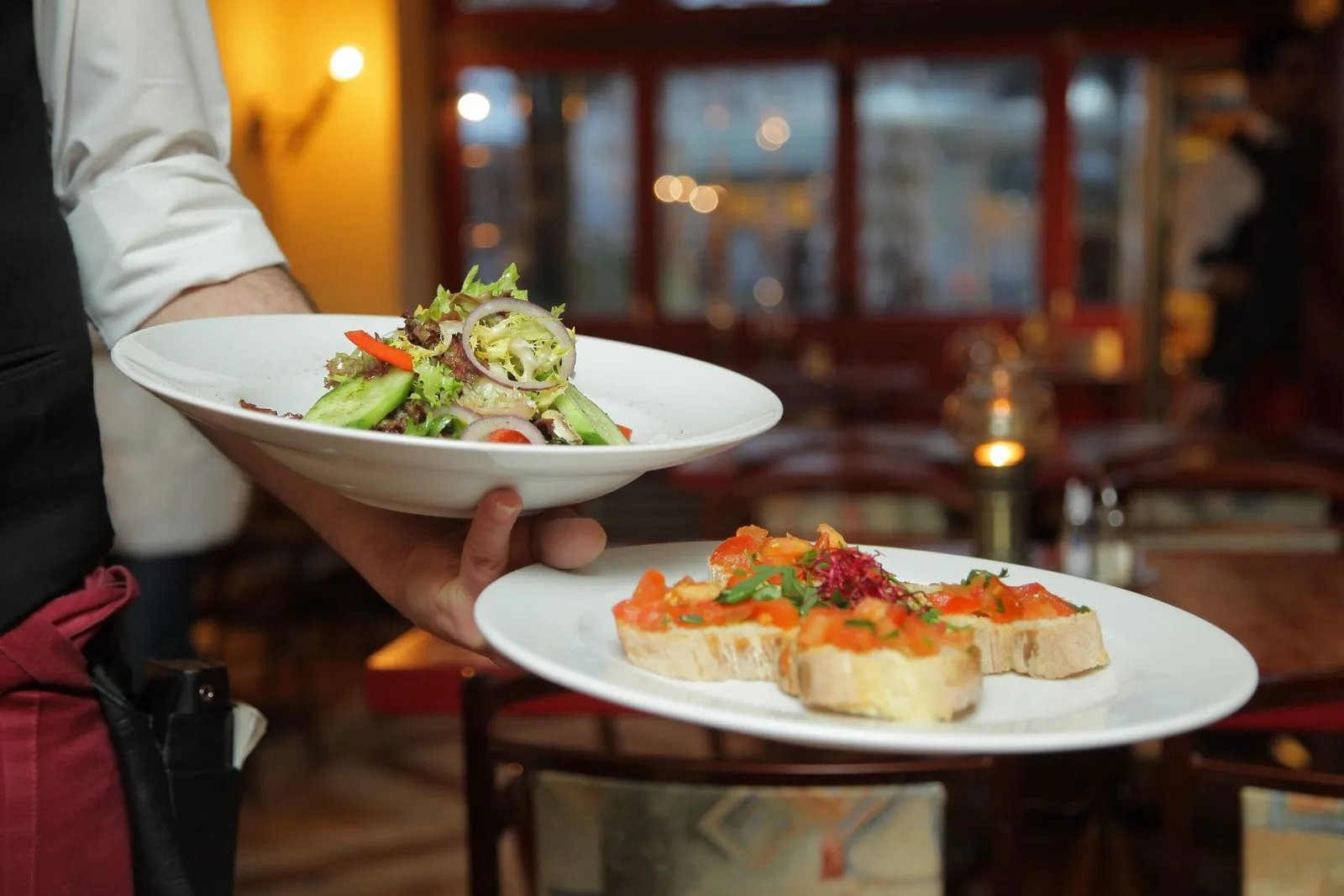 Un serveur apporte deux assiettes en salle