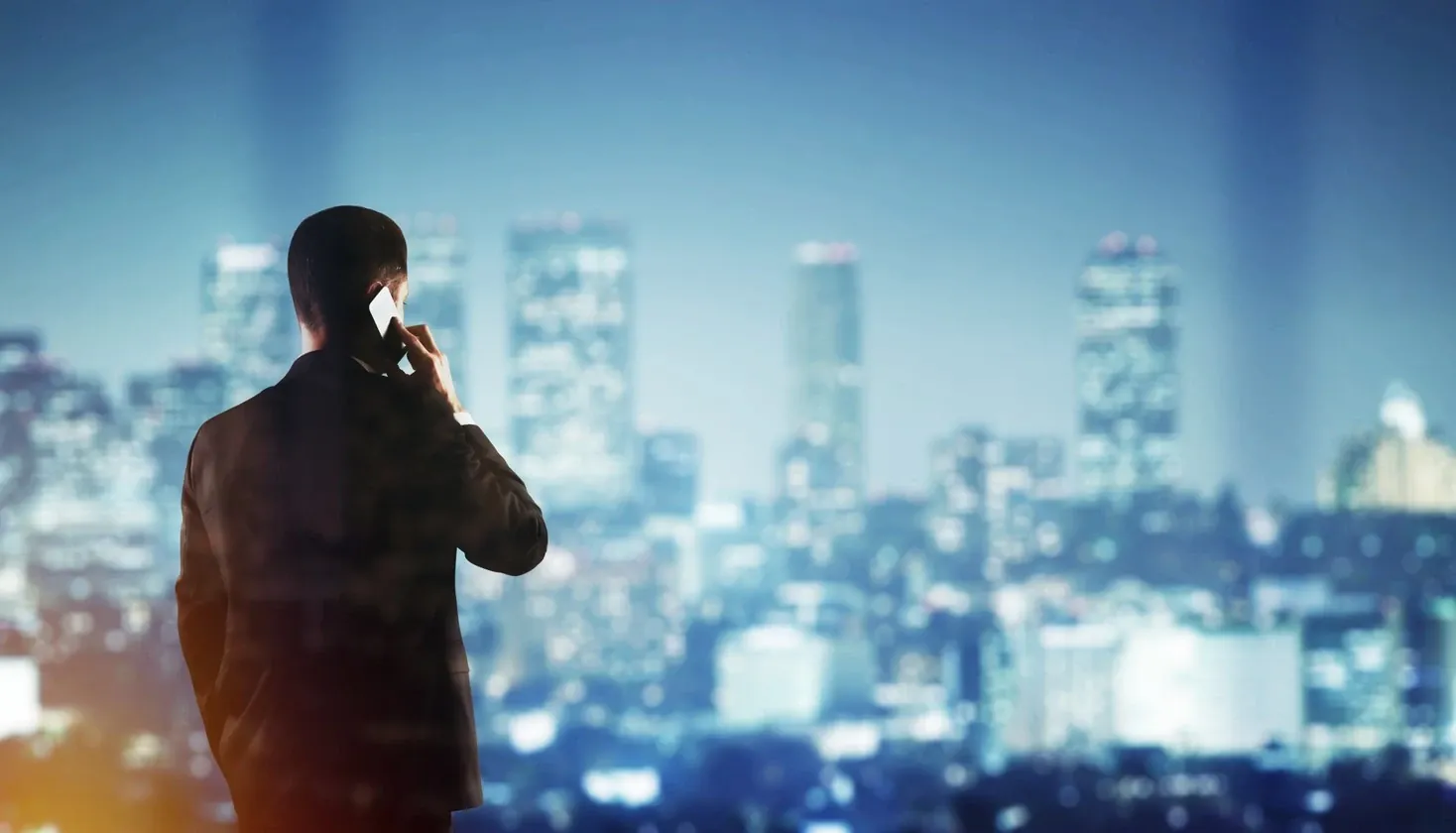 Un dirigeant au téléphone devant la ville, de nuit