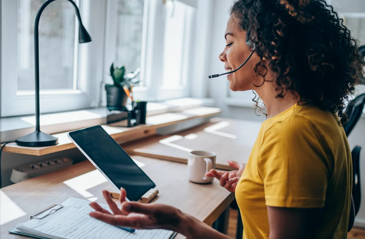 Salariée en télétravail téléphonant avec un casque depuis son ordinateur